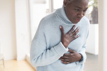 A woman with heartburn touching her chest in pain