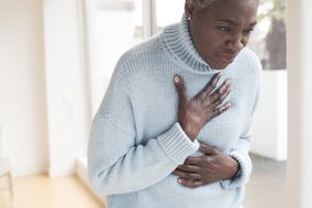 A woman with heartburn touching her chest in pain