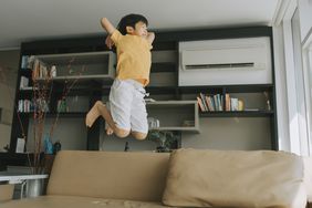 young boy with adhd showing signs of hyperactivity and jumping on the couch 