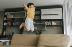 young boy with adhd showing signs of hyperactivity and jumping on the couch 