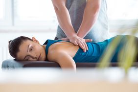 woman laying on massage table receiving therapy for back pain