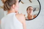 Mirror reflection of young female doing an anti-aging skincare routine