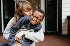 A mother and her adopted son smiling, laughing and cuddling on the front porch