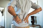 Rearview shot of an unrecognizable man holding his back in discomfort due to pain inside at home
