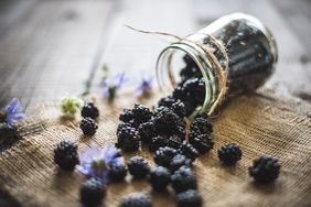 A mason jar of blueberries overturned over a table
