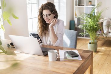 Smiling woman in front of computer and phone