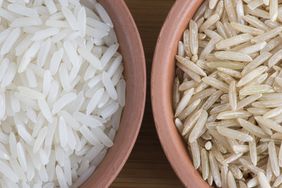 A close up of a bowl of white rice and brown rice next to each other