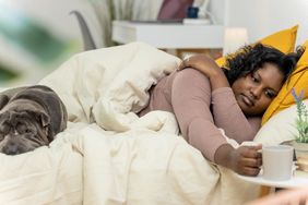 A woman reaching for a cup of coffee while in bed