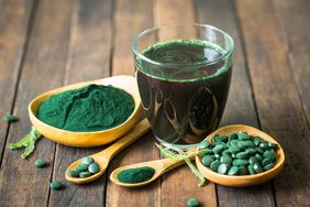 Healthy spirulina drink in the glass and chlorella tablets