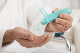 Close up of senior's hands taking pill from pill organizer