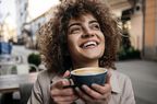Beautiful young woman smiling drinking cup of coffee outside
