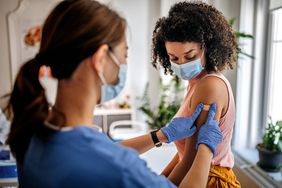 Doctor putting a bandaid on a woman's arm after a shot.