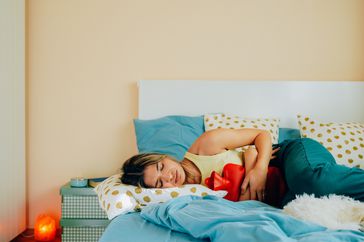 woman with endometriosis lying in bed with pain 