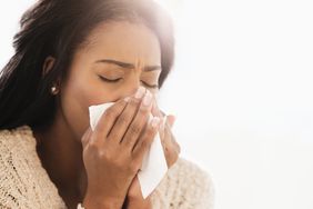 A mixed-race woman blowing her nose