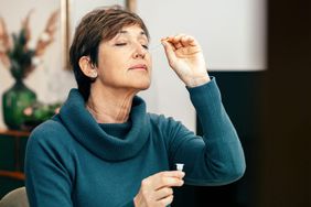Portrait Senior woman sitting, doing a test for COVID-19, Flu and RSV at home with kit. Introducing nasal swab test for possible infection.