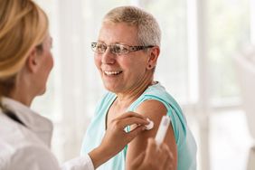 Doctor cleans a smiling woman's arm before giving her a shot