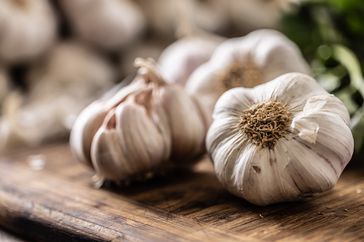Unpeeled garlic on a wooden cutting board