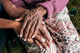 photo of older Black hands on top of younger Black hands.
