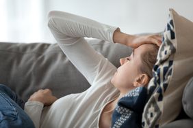 person laying on couch with hand on head