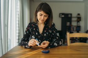 woman sits at the table and measures her blood sugar levels