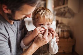 a dad helping his son with RSV blow his nose