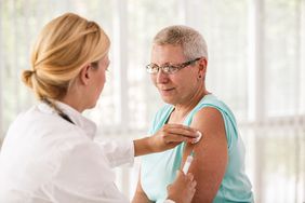 Doctor giving flu shot to senior female patient