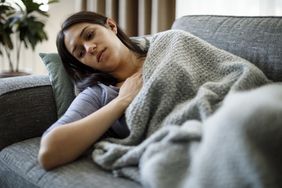 woman lying on couch under blanket