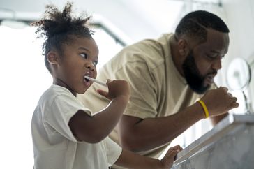 little kid and dad brushing teeth