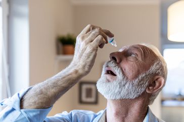 older person putting eyedrops in eye