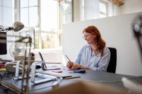 Red headed White female working at her desk having a video call on her laptop