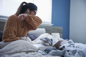 Woman sitting in bed coughing