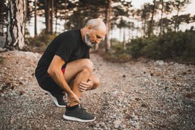 older man experiencing ankle pain while out on a walk