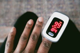 Close-up of unrecognizable black woman using a pulse oximeter to check her blood oxygen saturation level and heart rate