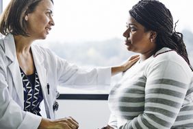 Female doctor consoling young woman in hospital