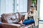 Shot of a man having a warm drink while recovering from an illness on the sofa at home