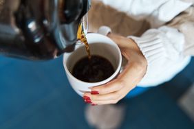 Person pour coffee from coffee pot into a mug