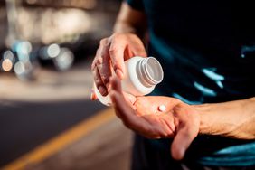 man holding a medicine bottle in one hand and pill in the other