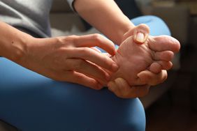 Female scratching the bottom of her foot while sitting down