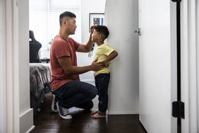 Father measuring son's height against a wall