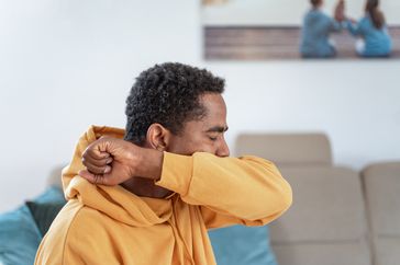 person coughing into their elbow