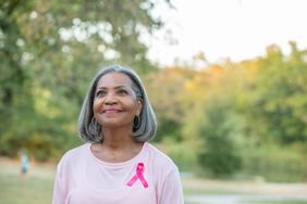 person wearing pink shirt with breast cancer awareness ribbon on