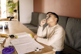 Young male child looking up sitting at table with notebook and fidget spinner in front of him
