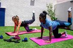 Two females doing leg lifts outdoors on yoga mats