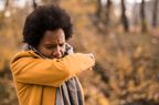 person outside coughing into arm