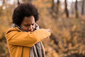 person outside coughing into arm