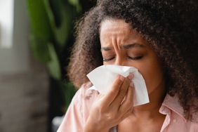 person sneezing into a tissue