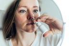 Woman cleaning her nose with salt solution in the mirror