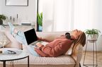 Top view above of a young casual woman in headphones sleeping with gadgets in their hands on cozy sofa in living room keeping eyes closed