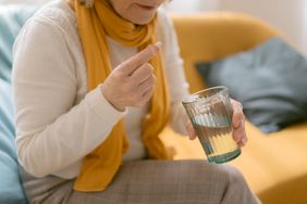 older woman taking an antibiotic with water