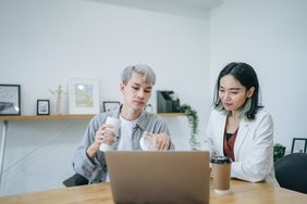 Two people drinking coffee looking at computer
